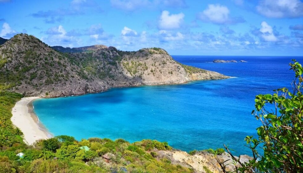 Une vue côtière époustouflante avec des eaux bleues claires, une plage et des montagnes escarpées entourant la baie sereine.
